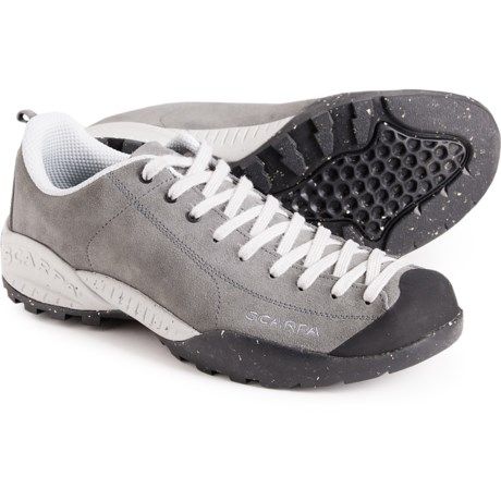 a pair of grey shoes with white laces on them and black bottom soles