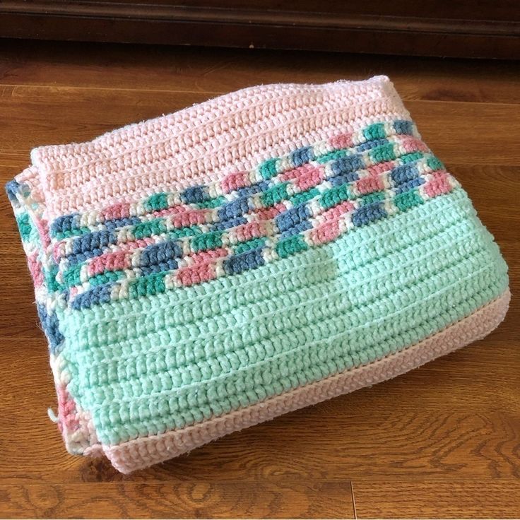 a crocheted blanket sitting on top of a wooden floor