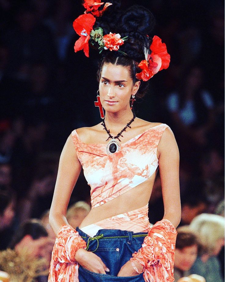 an instagram photo of a woman with flowers in her hair wearing a crop top and denim shorts