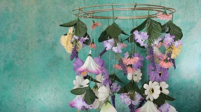 a wind chime with flowers hanging from it's sides on a blue wall