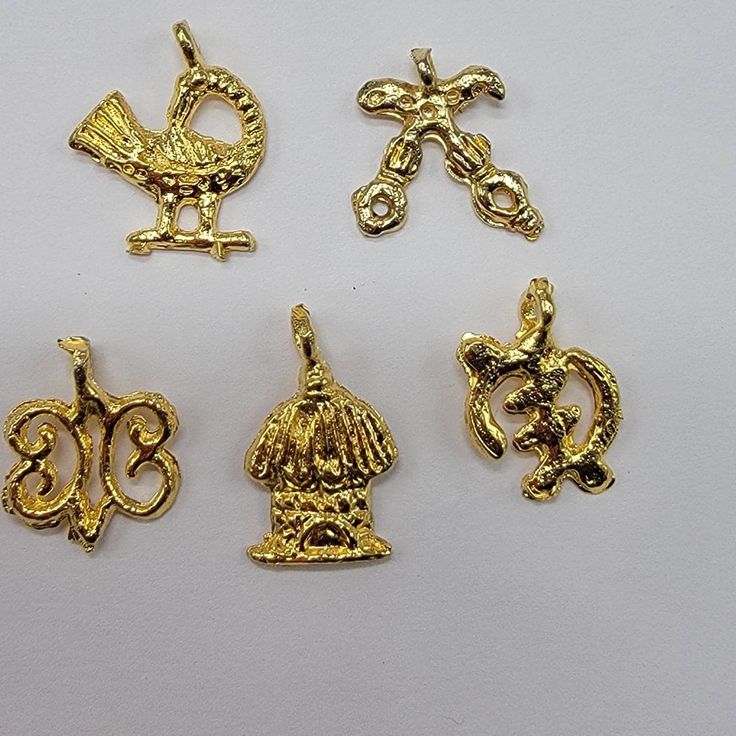 four gold charms are shown on a white surface, including one with an elephant and the other with a bird