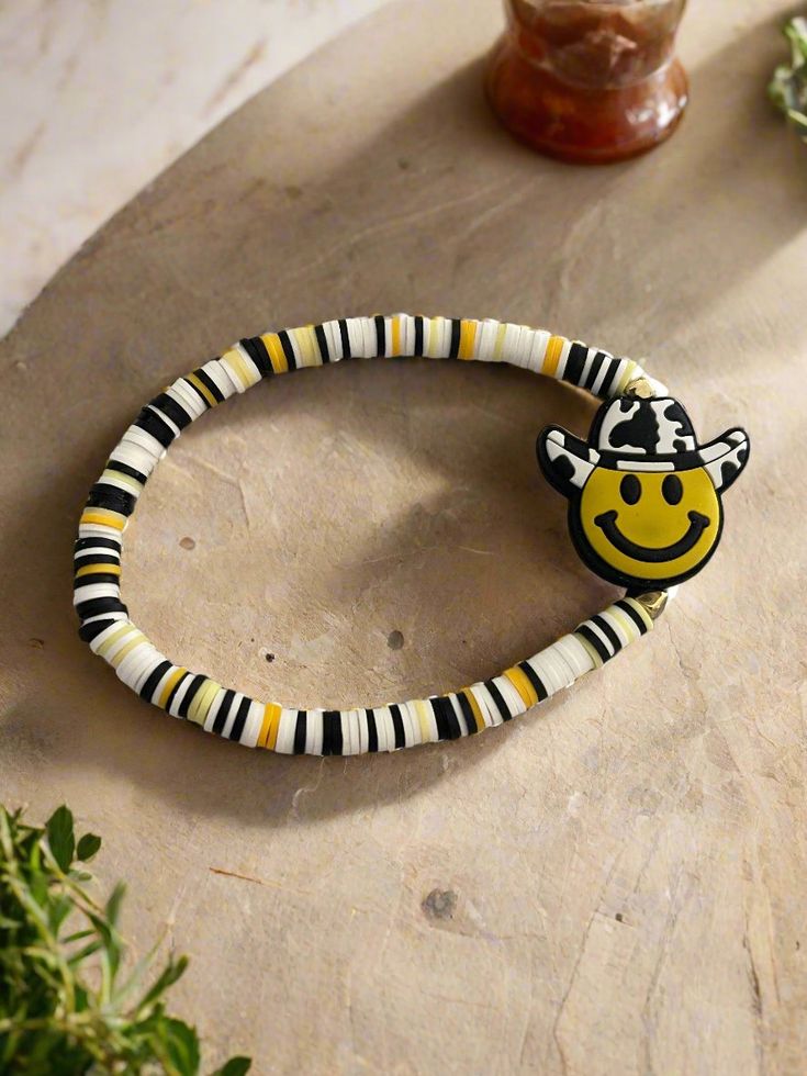 Description Get ready to add some quirk to your look with this super cute Smiley Face Cowboy Clay Beaded Stretch Bracelet! The center bead features a smiley face wearing a cowboy hat with cow print, surrounded by clay beads in fun white, black, and yellow colors. Yee-haw! Details fits 8" to 8 1/2" wrists Silicone Smiley Face in Cowboy Hat Bead: 28.8 mm x 31.2mm x 9.4mm black, white & yellow clay beads disc shaped clay beads Features One of a kind, fashion jewelry, everyday jewelry Great gift for Smiley Face Cowboy, Jewelry Everyday, Cute Smiley Face, Creative Memories Scrapbooking, Yee Haw, Clay Bead, Bracelet Ideas, Creative Memories, Black And Yellow