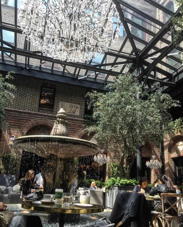 people are sitting at tables in the middle of an indoor cafe with chandelier overhead