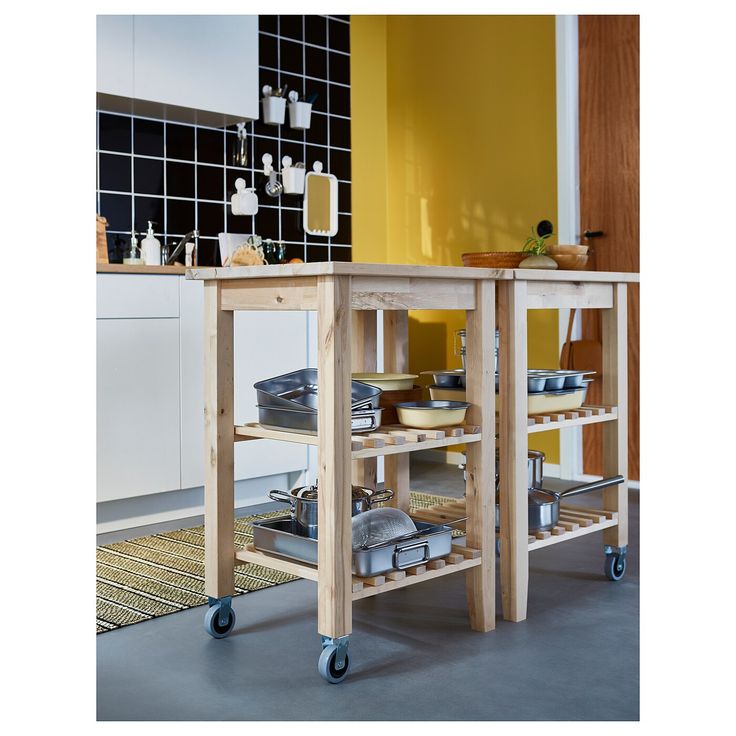 a kitchen island with lots of bowls and pans on it in front of a yellow wall