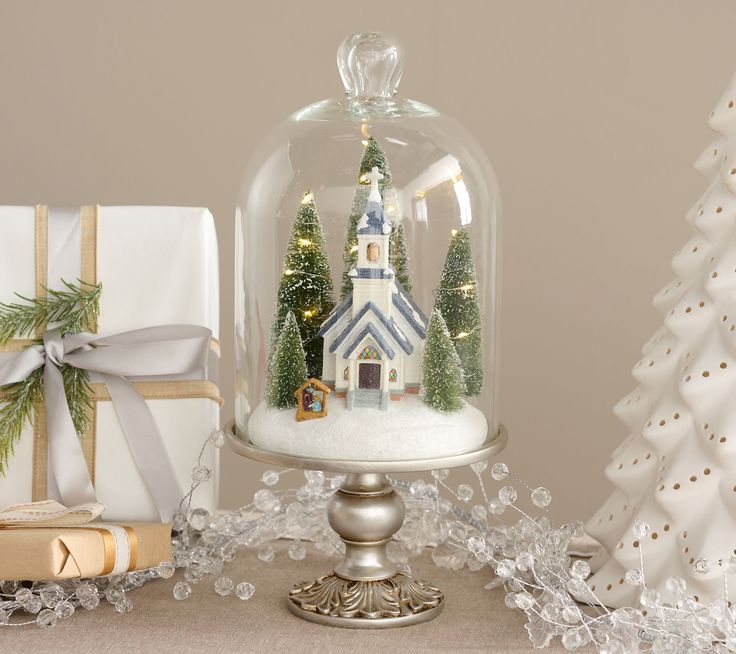 a christmas scene under a glass clochel on a table with presents underneath it