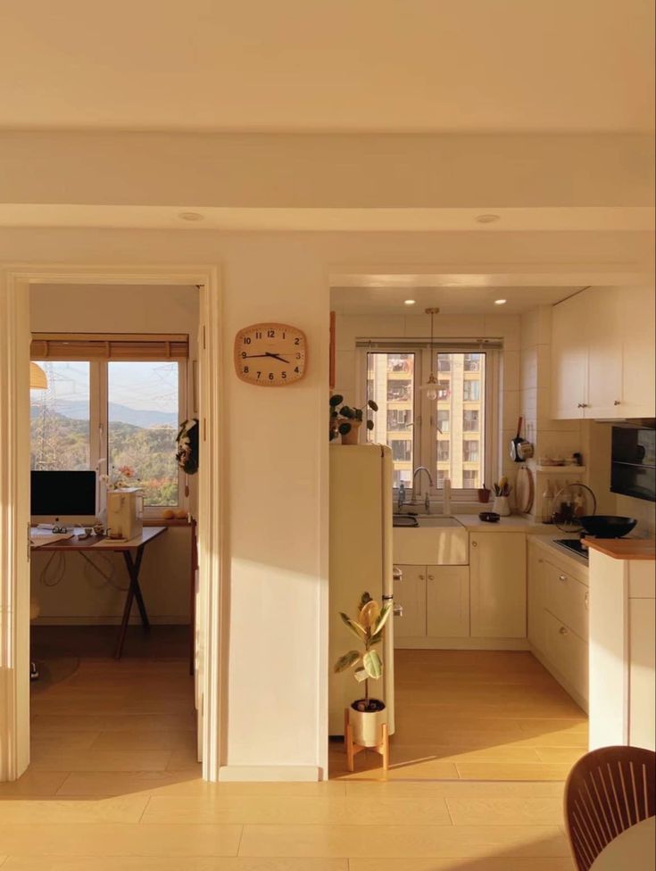 an open kitchen and living room with a clock on the wall