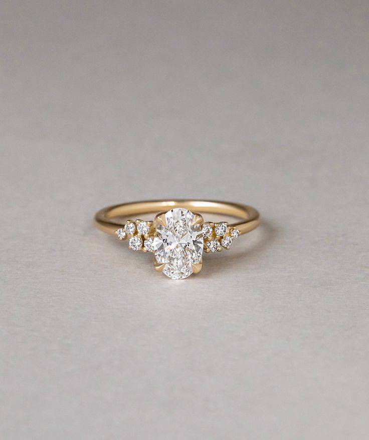 an oval diamond ring with three smaller diamonds on the band, set in yellow gold