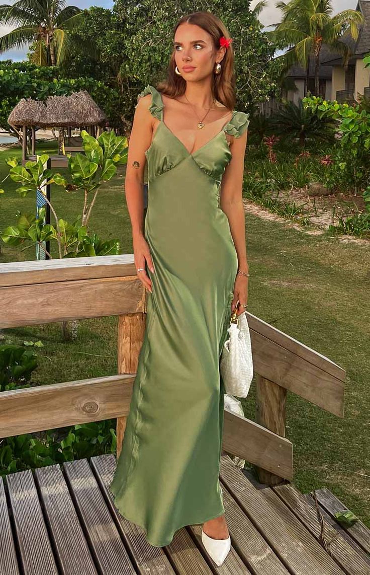 a woman in a green dress standing on a wooden deck