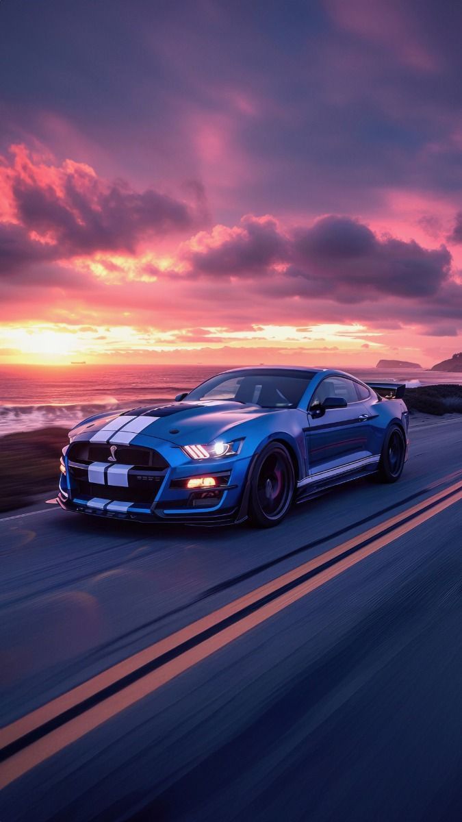 a blue car driving down the road with sunset in the backgroung behind it