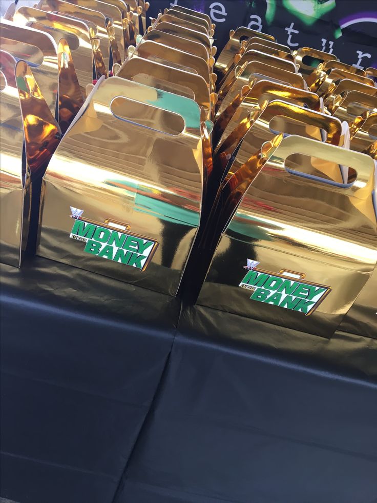 several shiny gold chairs are lined up on a black table with green and white signs