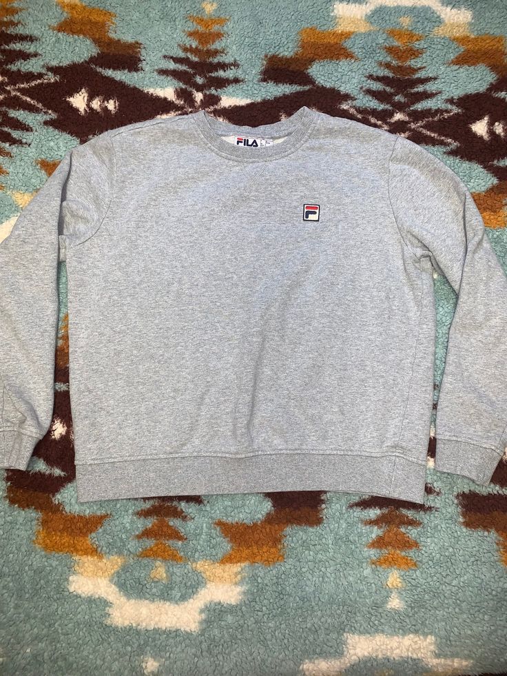 Step into retro style with this vintage grey Fila crewneck sweatshirt. Made from soft, cozy fabric, this classic piece features the iconic Fila logo in bold  across the chest. With its timeless design and relaxed fit, it's perfect for adding a touch of sporty flair to any outfit. Whether you're hitting the gym or just lounging at home, this vintage crewneck is sure to become a favorite in your wardrobe. Grab it now and embrace the vintage vibes! Specifications: Brand: Fila Color: Grey Size: SMALL  Condition: Vintage (minor signs of wear may be present, adding to its charm) Material: Cotton blend Care Instructions: Machine wash cold, tumble dry low Gray Fleece Crew Sweater, Gray Crew Neck Fleece Sweater, Casual Winter Sweatshirt With Logo Detail, Casual Winter Sweatshirt With Logo, Athletic Heather Crew Sweatshirt With Ribbed Cuffs, Gray Crew Neck Sweater For Streetwear, Classic Gray Sweatshirt With Ribbed Cuffs, Gray Crew Neck Urban Sweater, Urban Style Gray Crew Neck Sweater