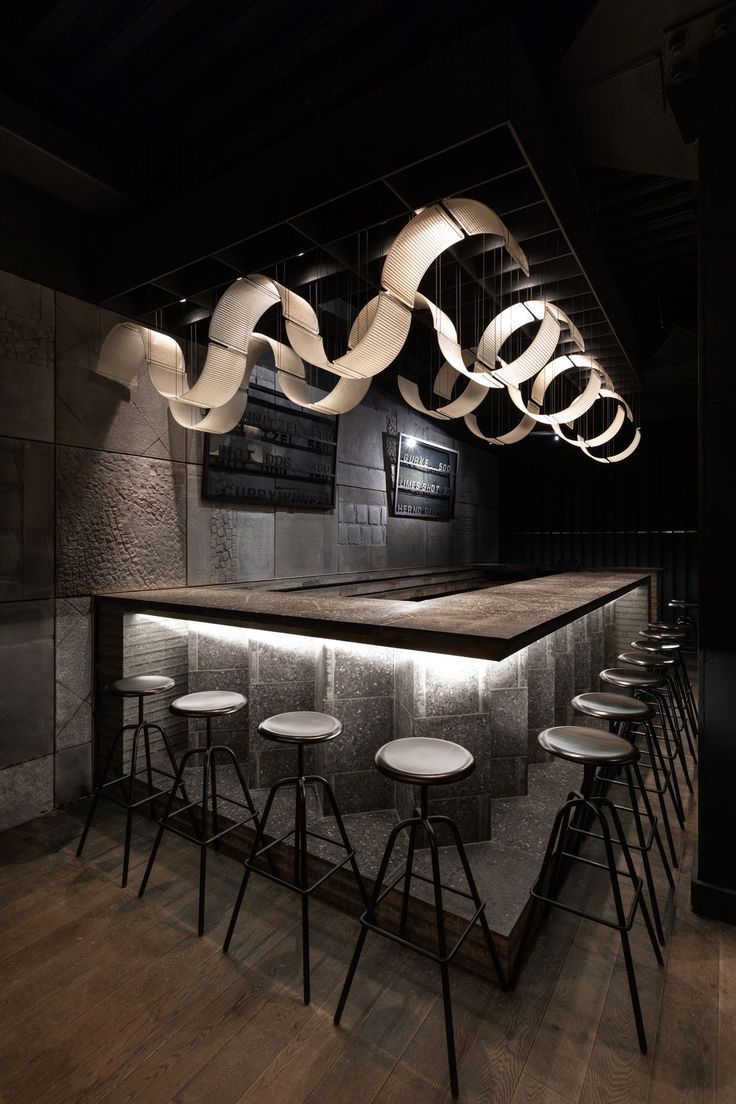 a bar with stools and lights hanging from the ceiling above it, in a dark room