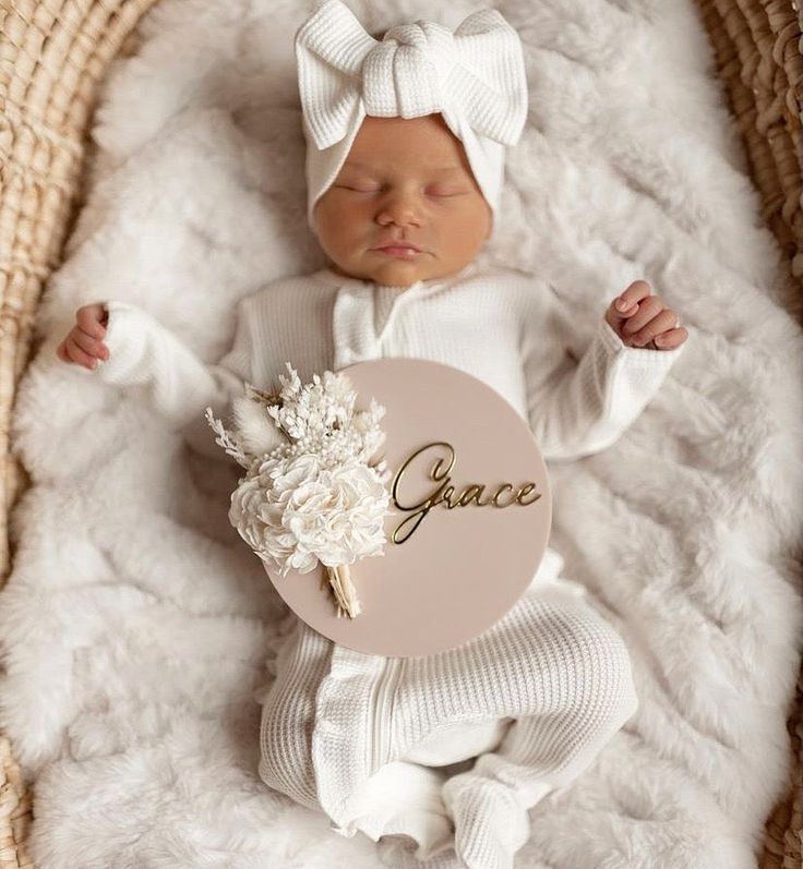 a newborn baby is wearing a white outfit and holding a name plate that says grace