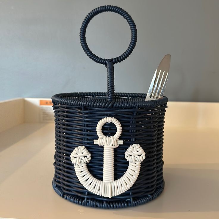 a basket with an anchor on the side holding utensils