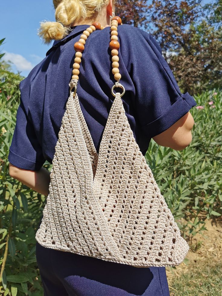 a woman carrying a crocheted bag with wooden beads on her neck and back