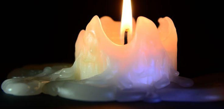 a lit candle sitting on top of a table next to some white rocks and water