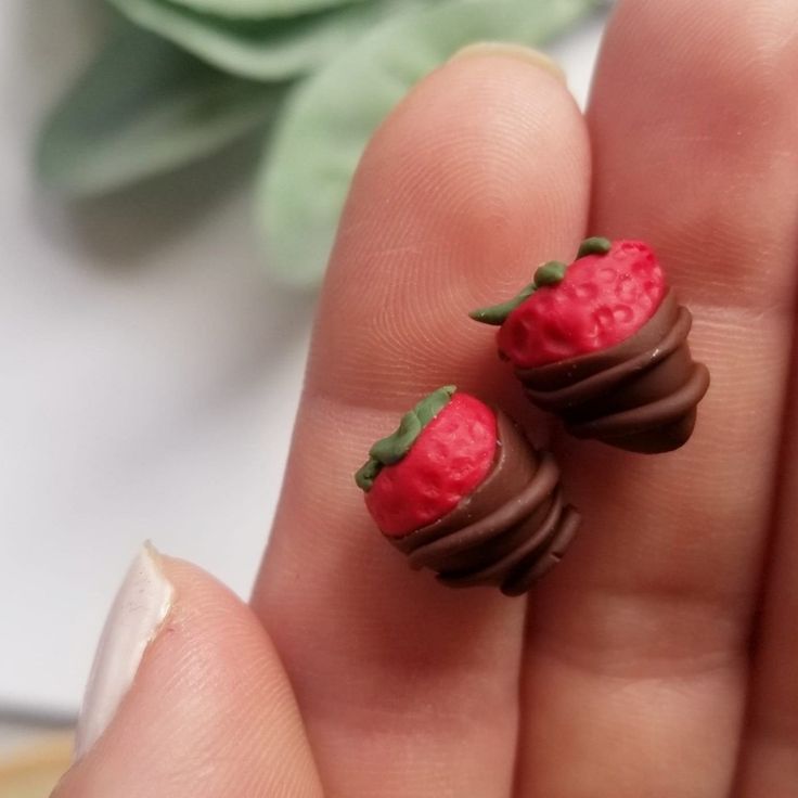 two tiny chocolate covered strawberries in the palm of someone's hand