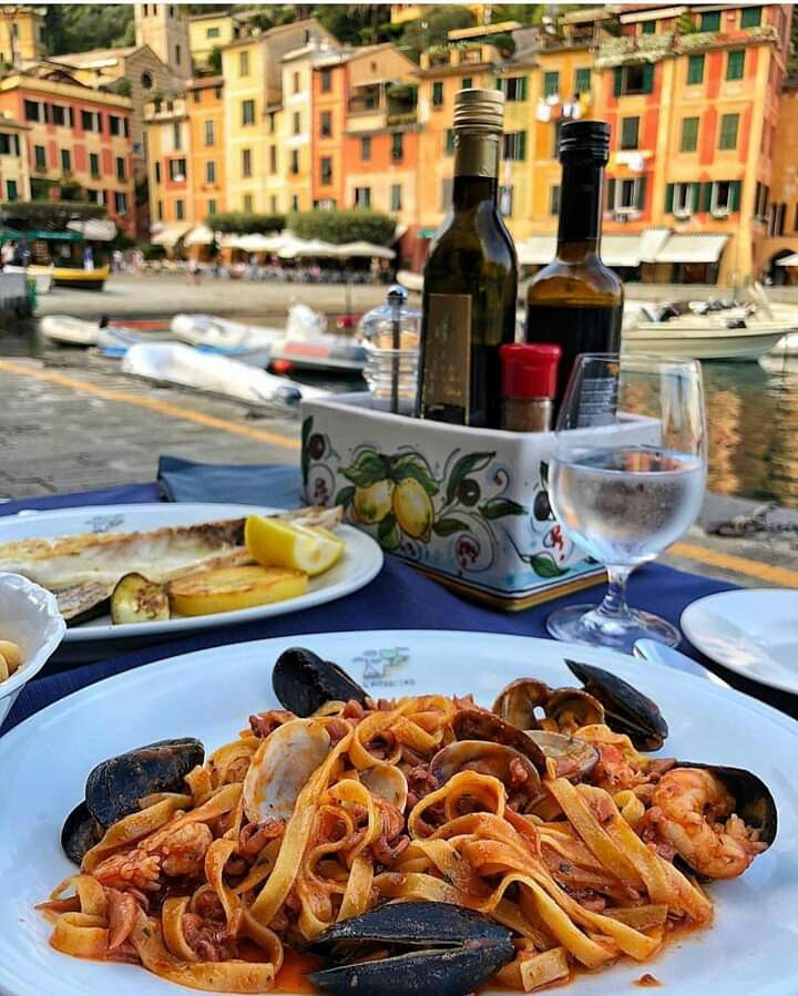 a plate of pasta with clams and mussels sits on a table outside