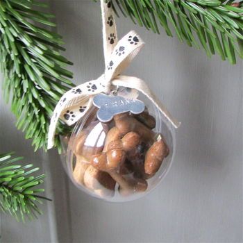 a glass ornament hanging from a christmas tree filled with nuts and dog paw prints