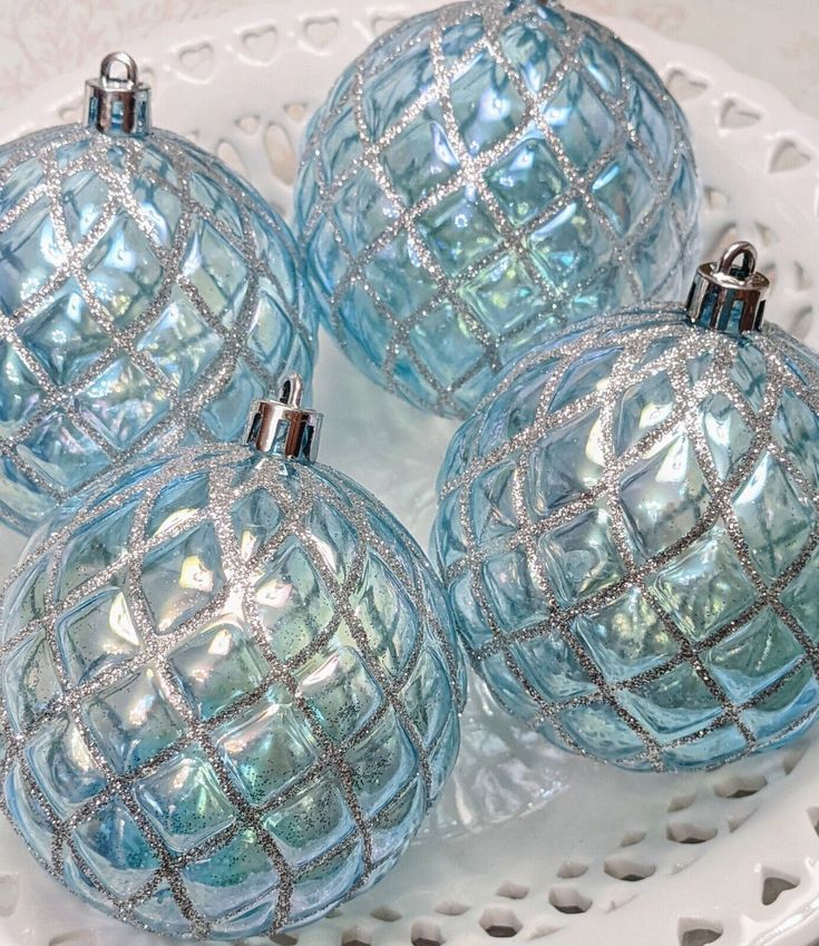 four blue glass ornaments sitting on top of a white plate