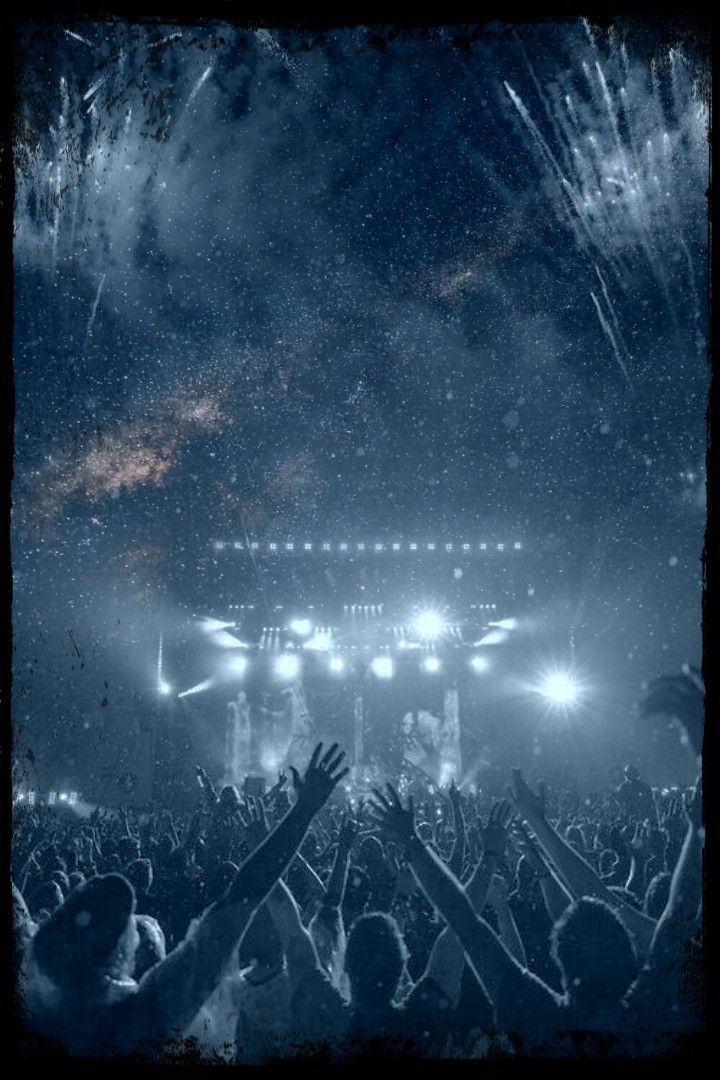 a crowd at a concert with their hands in the air and fireworks coming from above