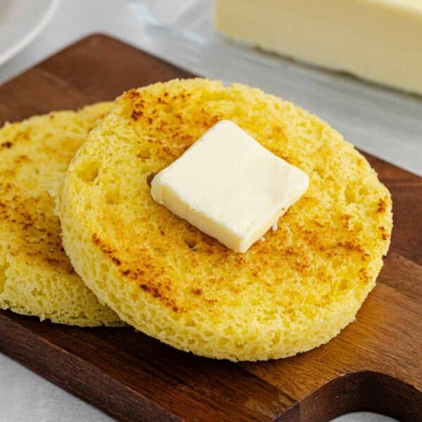 two pieces of bread sitting on top of a wooden cutting board with butter cubes