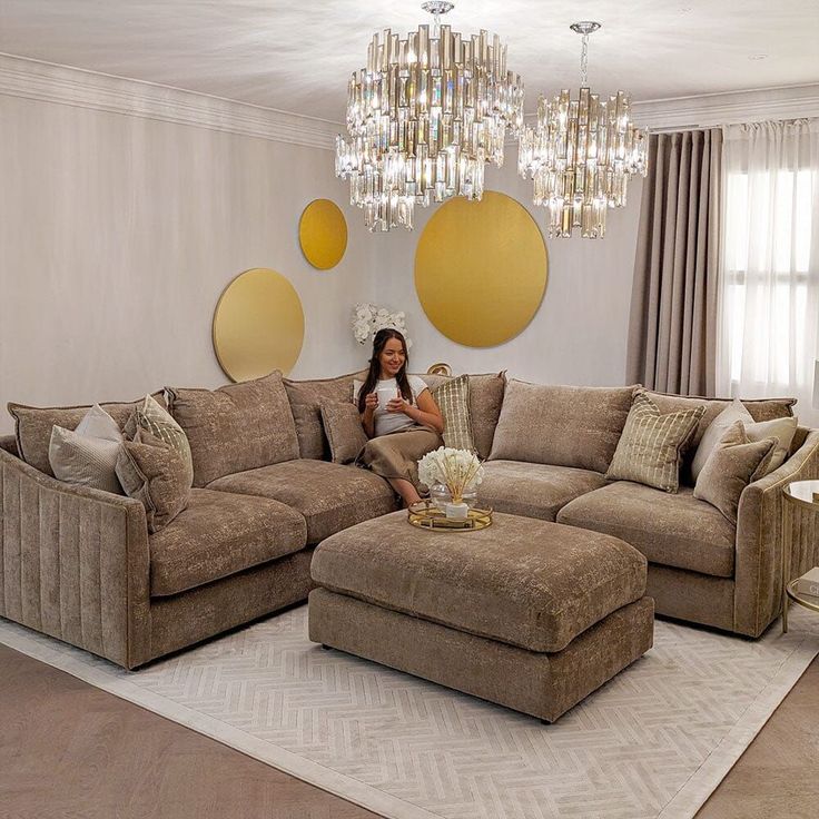 a woman sitting on top of a couch in a living room next to a chandelier