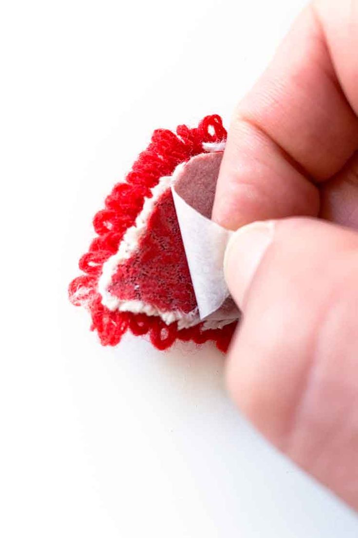 someone is holding a piece of fabric with red thread