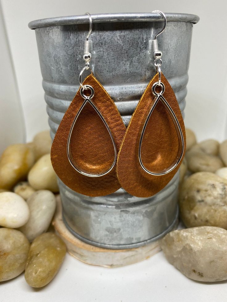 "Beautiful handmade item, real genuine leather earrings, includes a coordinating shape charm in a variety of metals and color options, bronze, silver and gold. Earring colors are black, rich cognac brown weathered leather and camel/mustard. Mustard is silver charm and hook Cognac brown is bronze charm and hook Black is gold charm and hook All available in round or teardrop. Round measures Aprox 1.5\" and teardrop Aprox 2\"" Handmade Leather Brown Earrings, Handmade Brown Leather Earrings, Handmade Brown Faux Leather Earrings, Brown Leather Earrings For Gift, Handmade Leather Teardrop Earrings, Everyday Hypoallergenic Brown Jewelry, Brown Metal Dangle Earrings, Brown Dangle Metal Earrings, Handmade Brown Earrings For Everyday Use