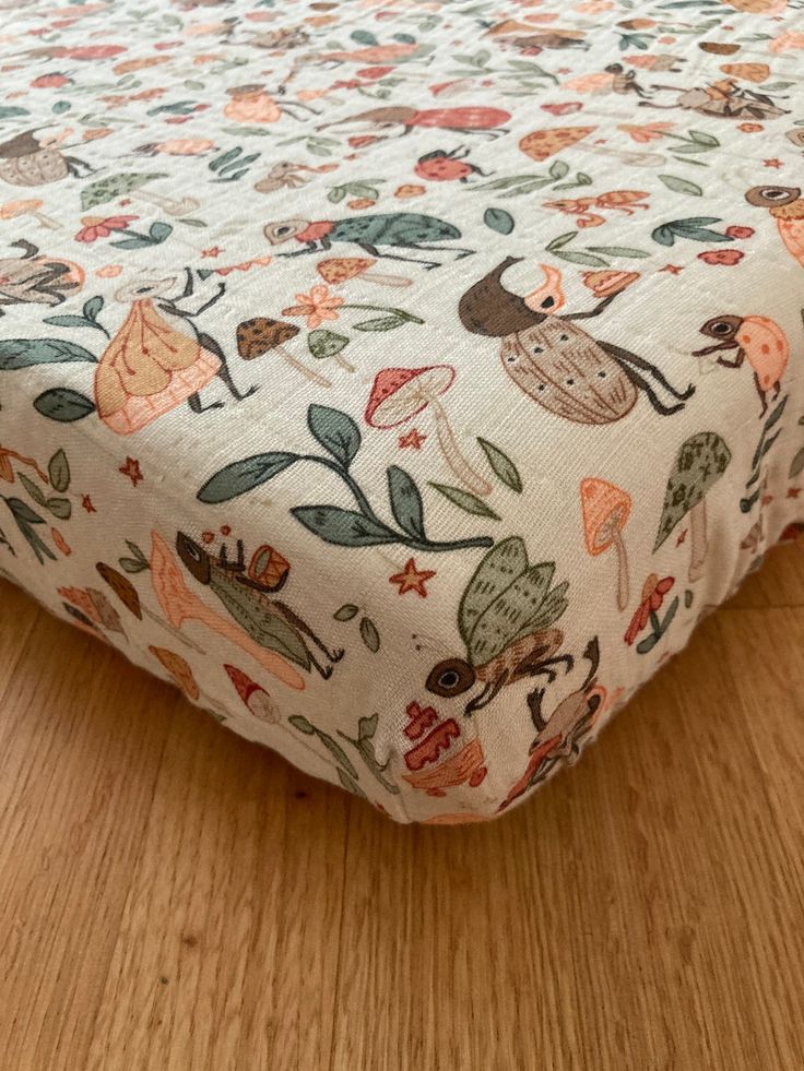 a close up of a bed on a wooden floor with an animal print cover over it