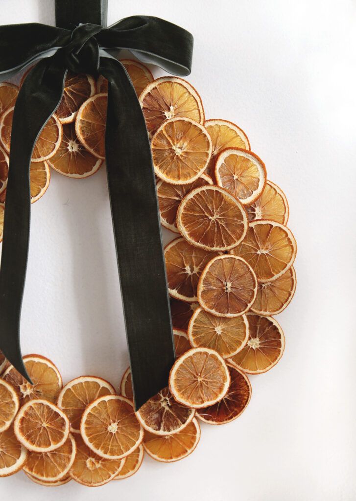 a wreath made out of orange slices with a black ribbon