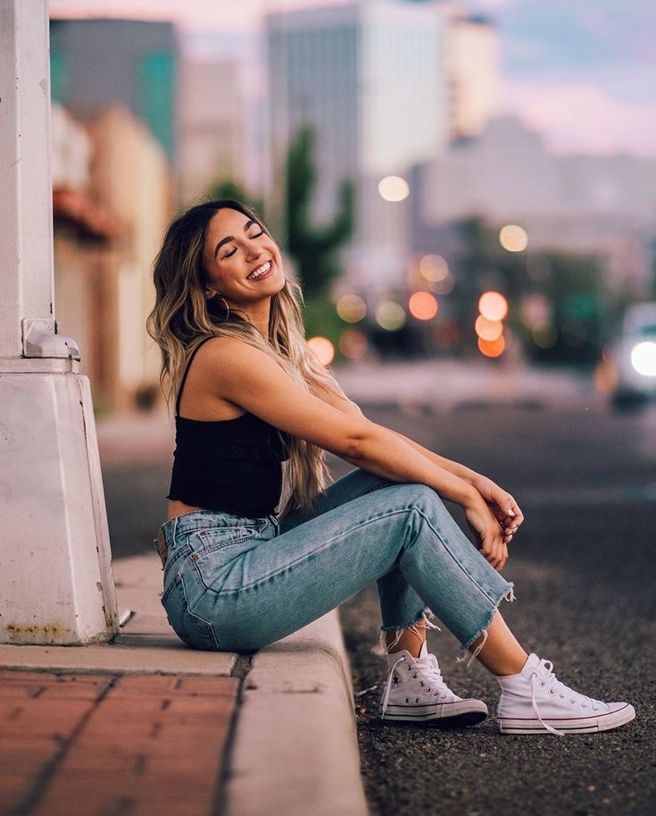 a beautiful young woman sitting on the side of a road