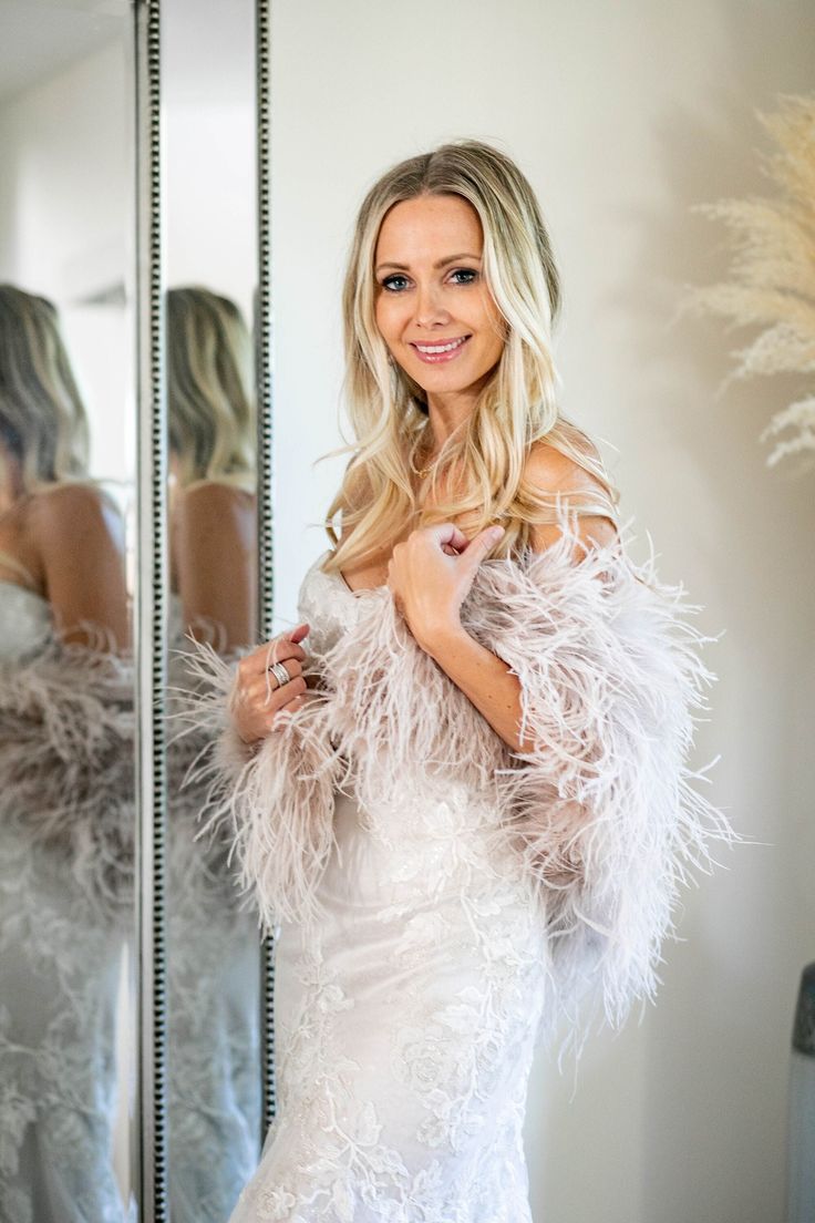 a beautiful woman in a white dress standing next to a mirror