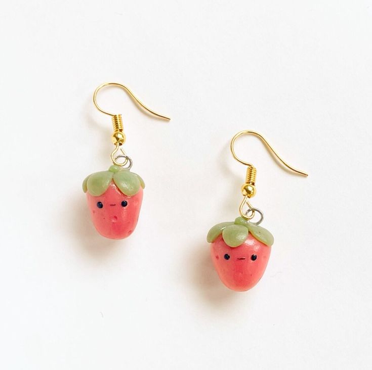 a pair of earrings with a strawberry on it's earring hooks are hanging from gold - plated wires