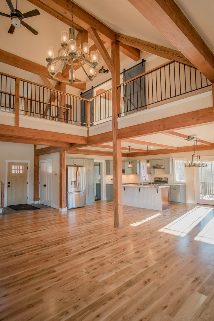 an empty living room with wood floors and chandelier hanging from the rafters