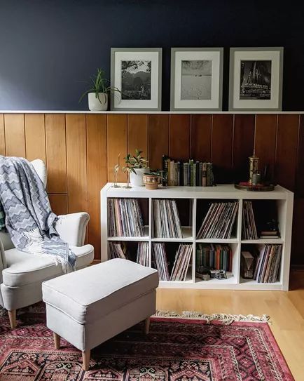 a white chair sitting in front of a book shelf filled with vinyl record's