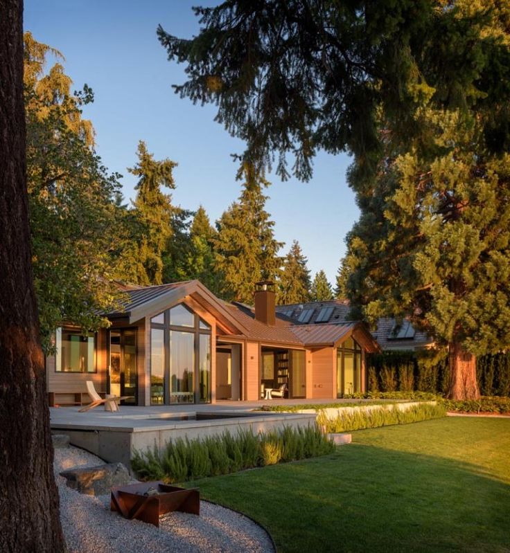 a modern house in the middle of some trees and grass at dusk with its lights on