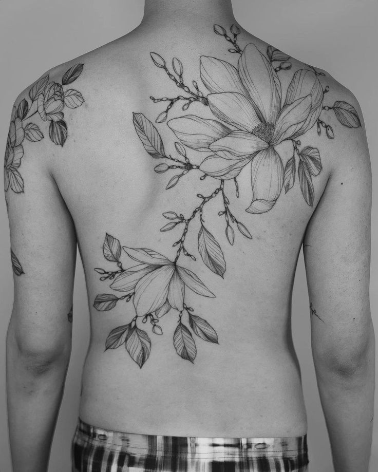 the back of a man's body with flowers tattooed on his upper and lower half