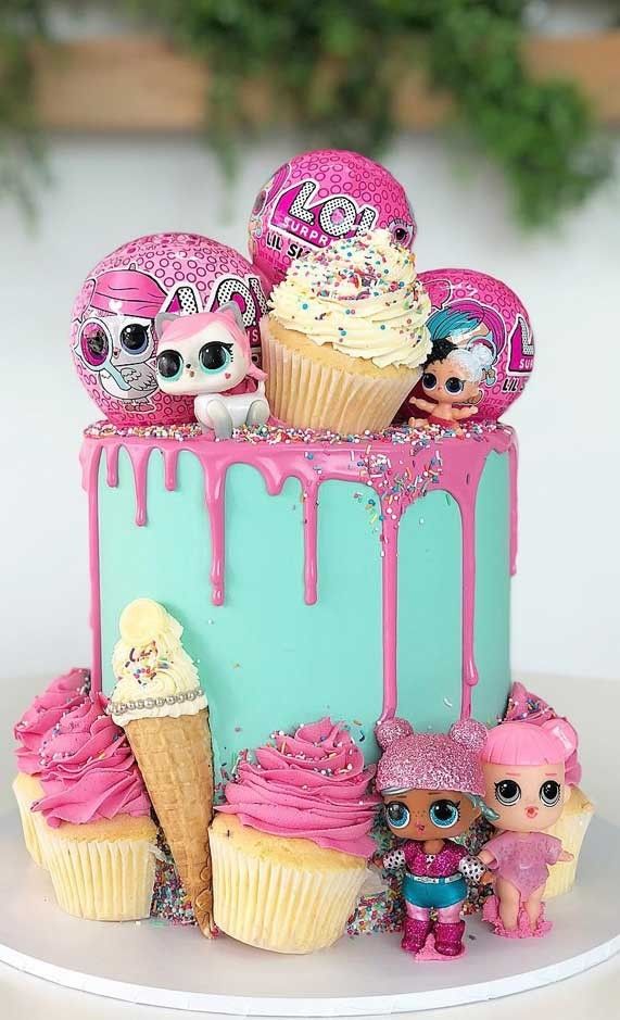 a birthday cake decorated with pink and blue icing, skulls, cupcakes, and toys