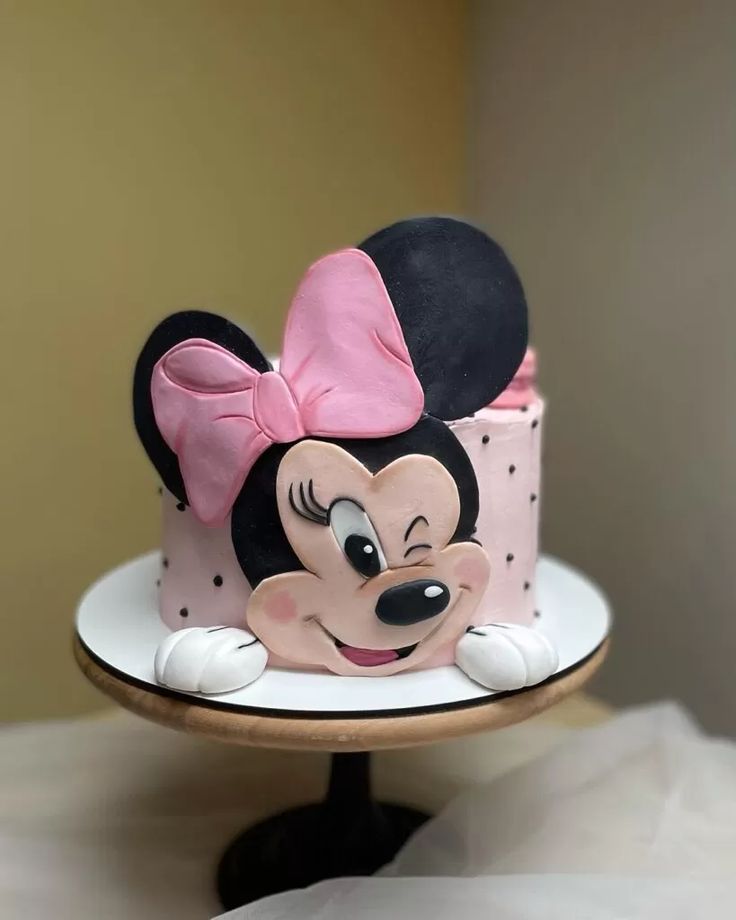 a minnie mouse cake on a plate with a pink bow around the top and black ears