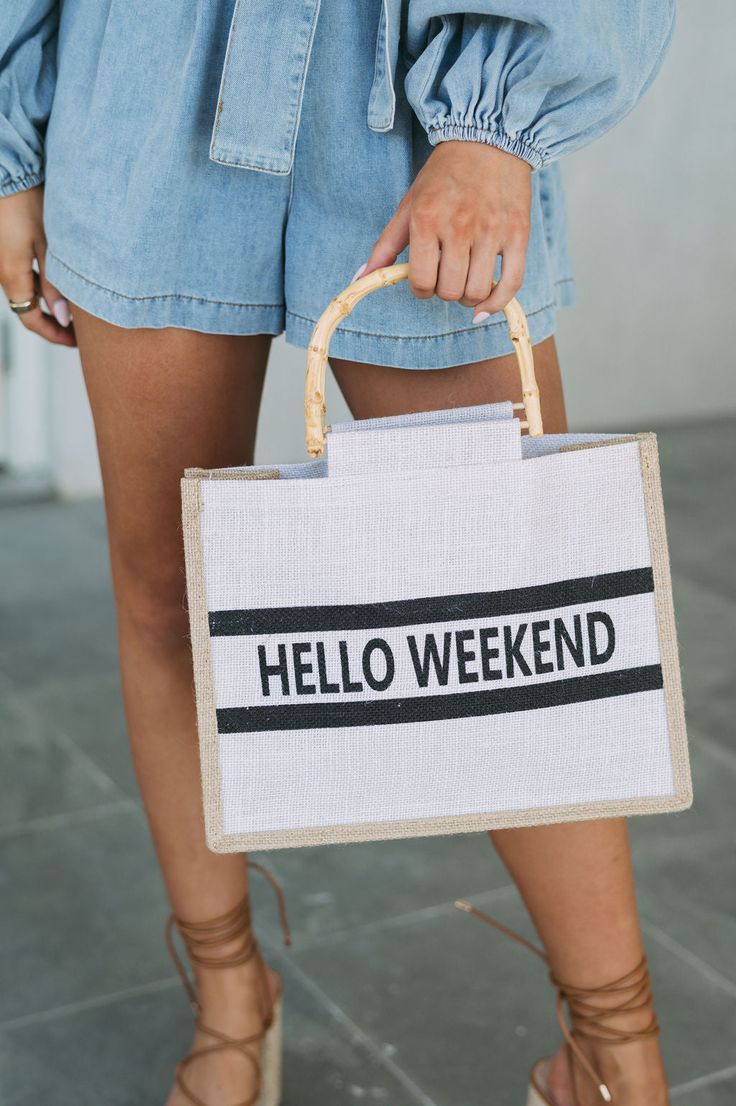 Elevate your weekend style with our Bamboo Hello Weekend Tote Bag. The beige square tote boasts a burlap-like fabric and brown trim, accented by bamboo straps. Featuring "Hello Weekend" on the front, this bag is perfect for a day out or a trip to the beach! Trendy Natural Canvas Bag In Rectangular Shape, Trendy Natural Rectangular Canvas Bag, Summer Rectangular Canvas Bag With Leather Handles, Canvas Bags For Spring Weekend, Trendy Summer Canvas Bag For Weekend, Trendy Summer Weekend Canvas Bag, Canvas Bag For Weekend In Spring, Rectangular Canvas Shoulder Bag For Weekend, Canvas Bag For Weekend And Spring Season