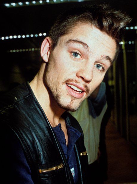 a man in a leather jacket smiling at the camera