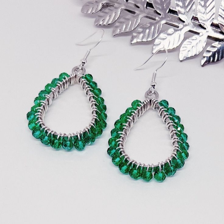 These lovely earrings are handmade using green crystal glass beads. The beads are carefully and individually wrapped around silver teardrop pendants with silver, tarnish-resistant wire and hang from hypoallergenic 925 sterling silver earring hooks. The earrings measure approximately 2" long from the top of the earring hook to the bottom teardrop pendant. (Please see the pictures that include a measuring tape and/or quarter for size reference.)  They are perfect to give as a gift or to treat yourself to something special.  Colors may appear slightly different in images when displayed on your screen. Cotton Filled Box Included. Handmade in the USA. ------  Find more Beautiful Pieces at AshbeesAccessories 🛍 Gemstone Necklaces: https://www.etsy.com/shop/AshbeesAccessories?section_id=24082817 Silver Beaded Teardrop Earrings As Gift, Silver Beaded Teardrop Earrings For Gift, Handmade Green Crystal Sterling Silver Earrings, Silver Teardrop Beaded Earrings With Faceted Beads, Green Teardrop Beaded Earrings With Wire Wrap, Green Teardrop Beaded Earrings With Wire Wrapped Detail, Teardrop Green Crystal Earrings, Green Teardrop Wire Wrapped Beaded Earrings, Green Wire Wrapped Crystal Earrings As Gift