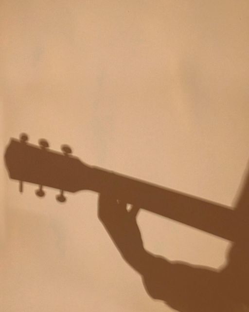 the shadow of a person holding an acoustic guitar