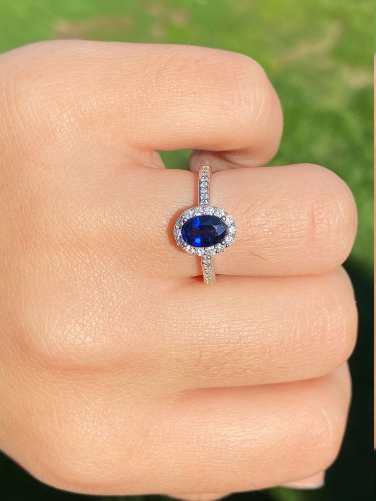 a woman's hand with a diamond and blue sapphire ring