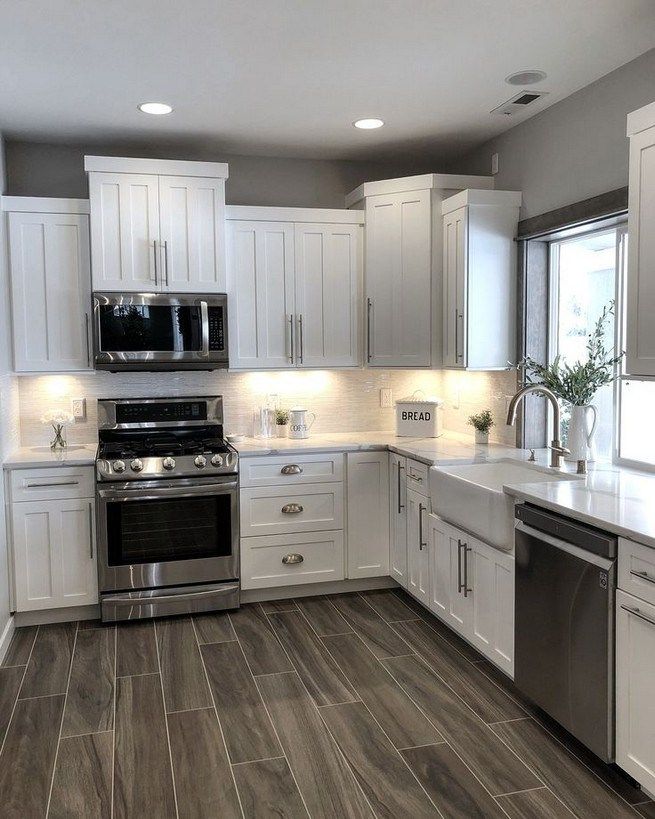 a large kitchen with white cabinets and stainless steel stove top oven, dishwasher, microwave and sink