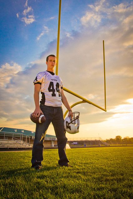 a man holding a football on top of a field with a pole in the background