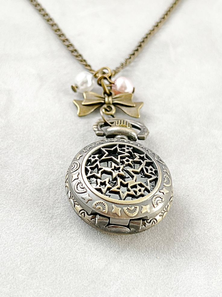 Antique bronze Pocket watch vintage necklace chain pearl charm This is a beautiful antique bronze quartz pocket watch pendant that is powered by quartz movement. Top cover flips open to view the white face dial with black  numbers.    Watch measure 1.75 inches or 45mm. It is securely fastened with a sturdy matching 32" ( 80 cm) chain. This quartz watch is a wonderful keepsake. Watch: https://www.etsy.com/shop/NewJewelleryStory?ref=seller-platform-mcnav&section_id=17293743 My jewelry is not water Vintage Gold Pocket Watch In Stainless Steel, Steampunk Bronze Pocket Watch Gift, Vintage Bronze Metal Pocket Watch, Antique Quartz Pocket Watch As Gift, Antique Quartz Pocket Watch Gift, Vintage Alloy Necklaces, Vintage Antique Gold Pocket Watch As Gift, Antique Gold Quartz Pocket Watch As Gift, Antique Bronze Metal Pocket Watch