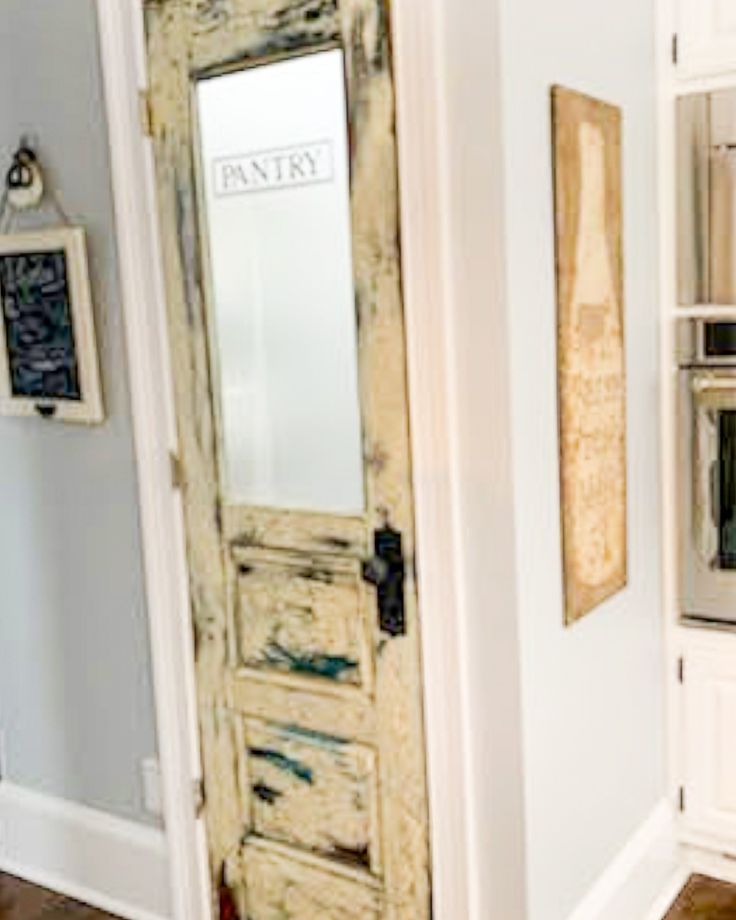 an old door in the corner of a kitchen with white cabinets and wood flooring