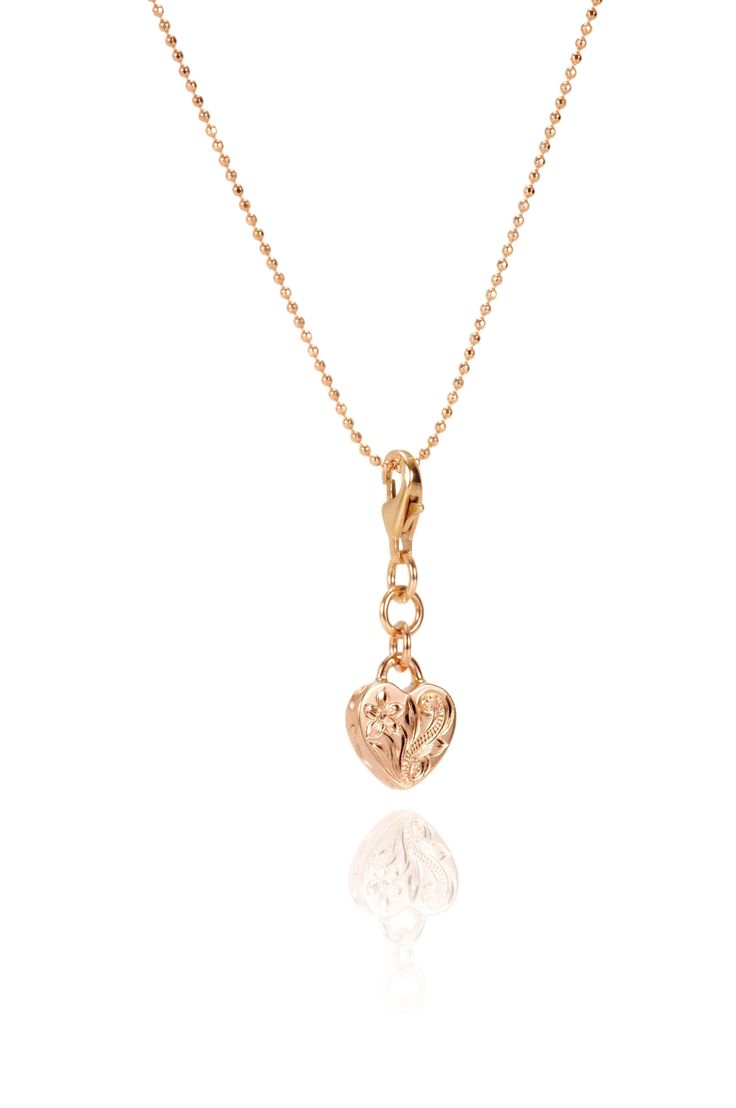 In this photo there is a 14k rose gold heart charm with plumeria engraving. Rose Gold Plated Heart Charm Necklaces, Gold Flower Pendant Jewelry With Heart Charm, Rose Gold Plated Charm Necklaces With Heart Charm, Rose Gold Heart Charm Necklace, Gold Plated, Gold Plated Heart Charm Pendant, Rose Gold Plated Charm Necklace With Heart Charm, Engraved Rose Gold Heart Pendant Charm Necklace, Elegant Heart Charm Pendant, Rose Gold Heart Pendant Jewelry With Flower Charm